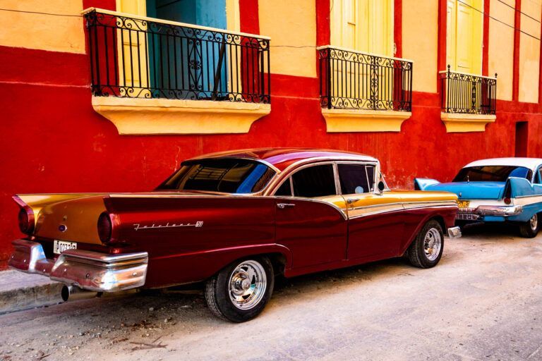 Beautiful cars in Santiago de Cuba matching colors with the houses shot in golden hour